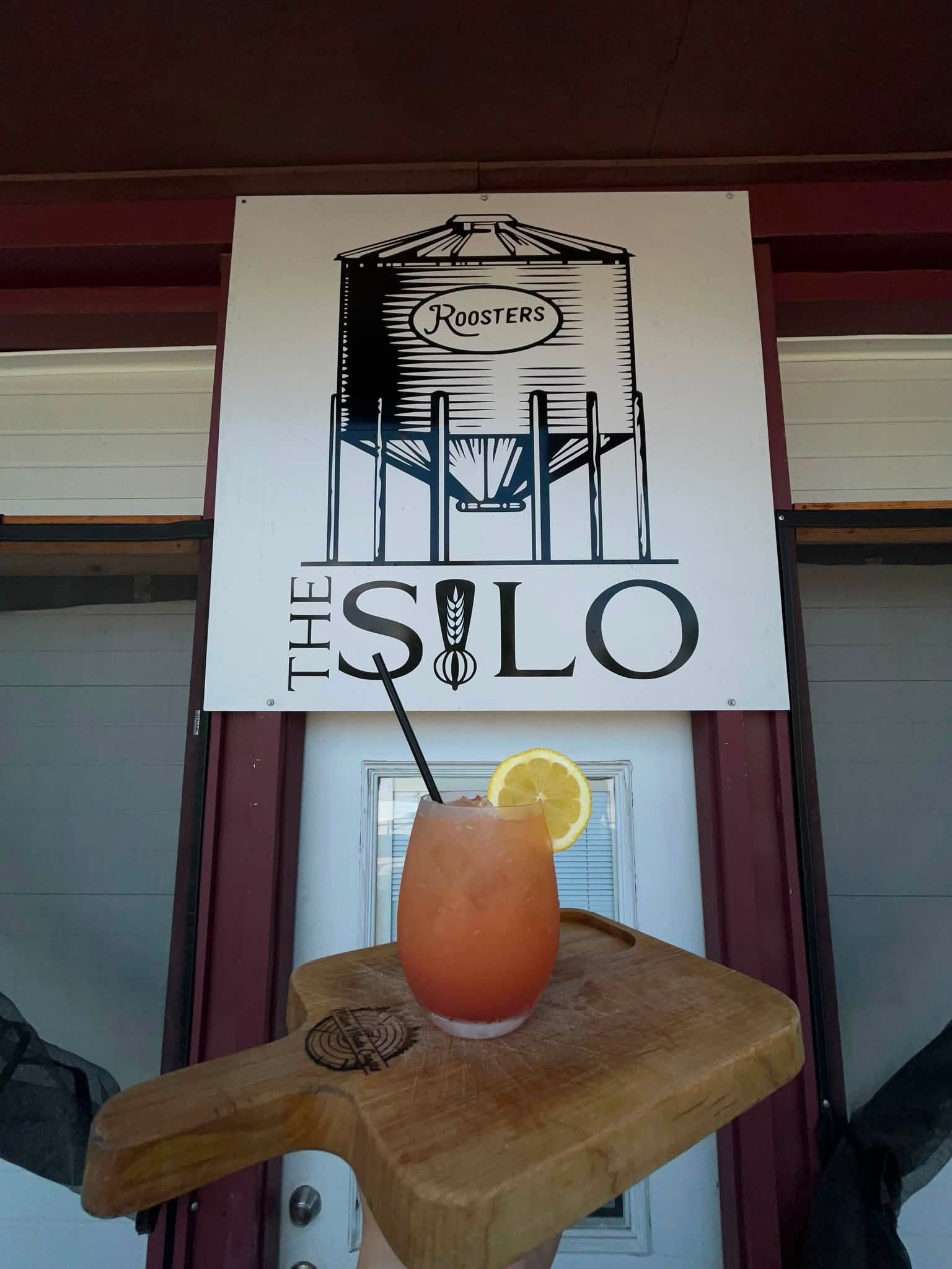 The Silo — Roosters grain bin sign above the entrance with a mason-jar cocktail